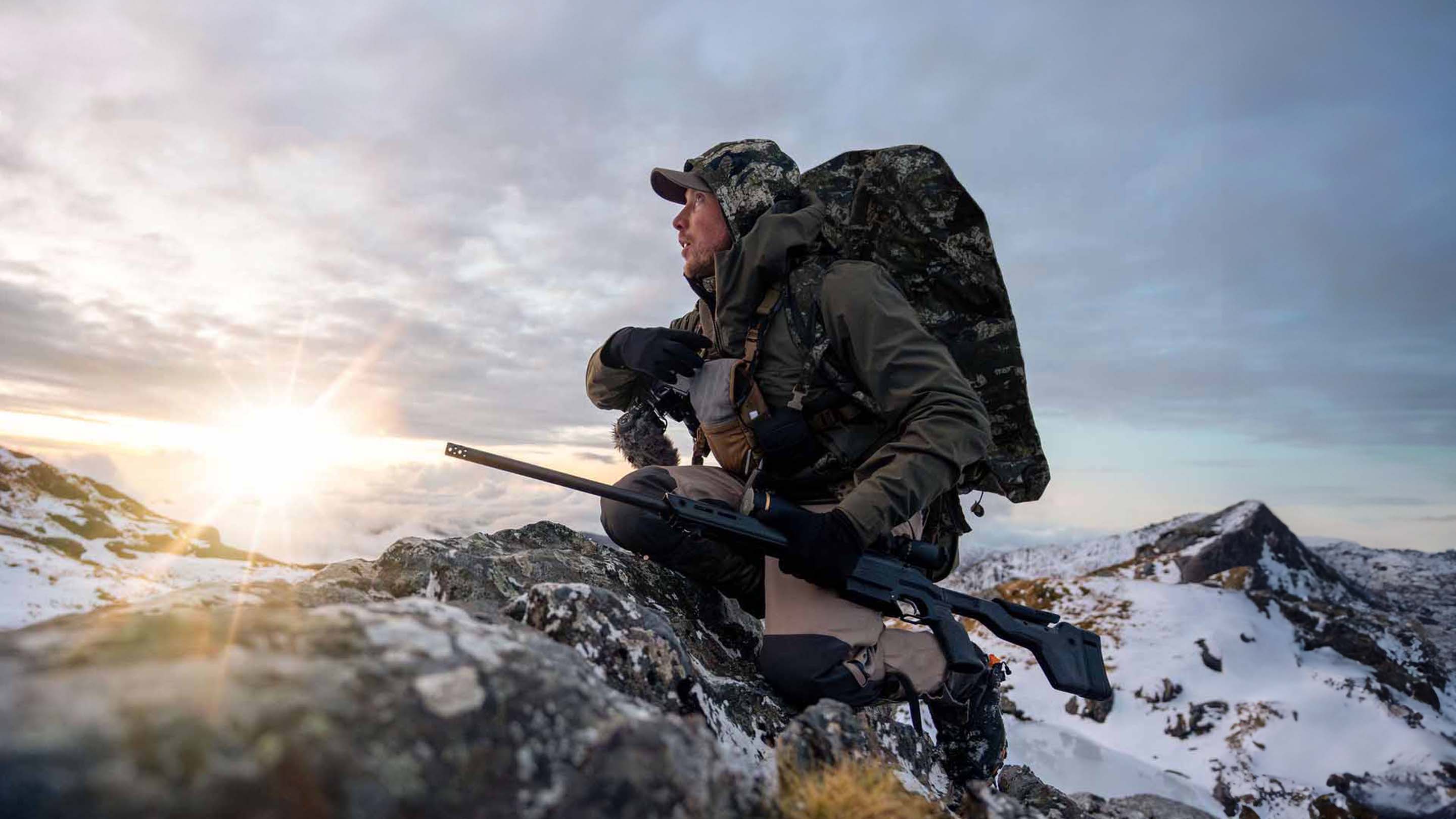 J.E. Wilds sitting on snowy mountain in Huntech's Expedition Range gear
